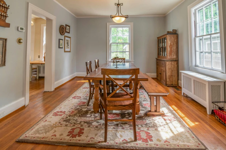 a dining room with a wooden table and chairs, by Pamela Drew, pexels contest winner, areas rugs, hardwood floor, bright sky, classic portrait