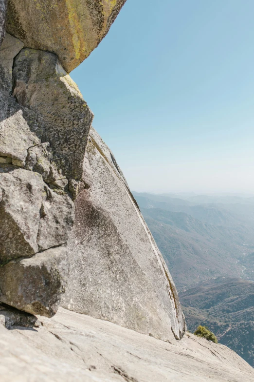 a person standing on top of a large rock, by Kristin Nelson, trending on unsplash, arabesque, helmet view, granite, panoramic view, central california