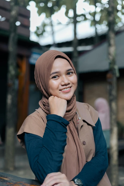 a woman wearing a hijab sitting on a bench, inspired by Nazmi Ziya Güran, unsplash, smirking at the camera, headshot profile picture, indonesia, teacher