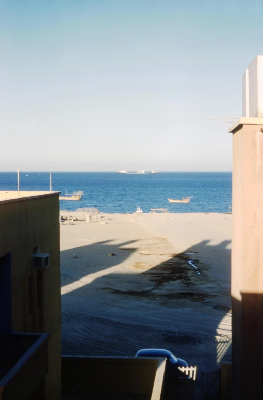 a view of the ocean from a balcony, inspired by Thomas Struth, old jeddah city alley, low quality grainy, military camp in the background, ships