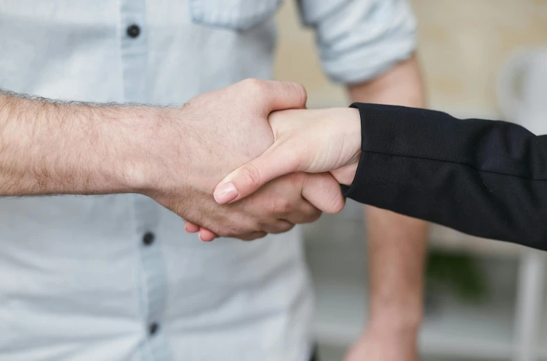 a close up of two people shaking hands, colour photograph, customers, medium height, embracing