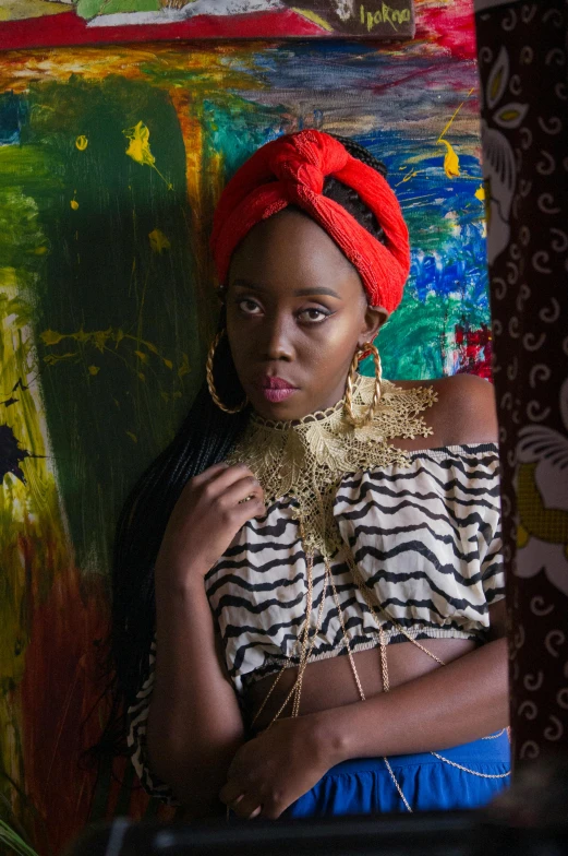 a woman standing in front of a painting, an album cover, inspired by Ras Akyem, pexels contest winner, red headband, intricate african jewellery, “ sensual, photo from a promo shoot