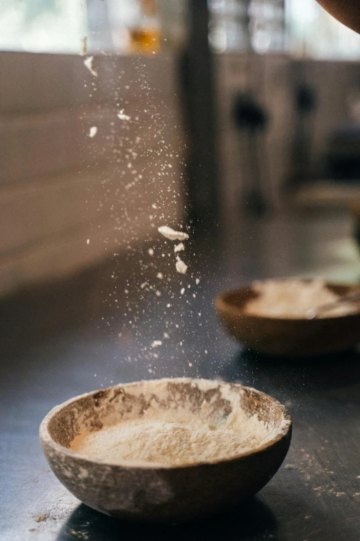 a person sprinkling flour into a bowl, a portrait, unsplash, crust, plating, dynamic closeup, tall