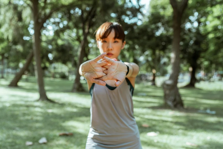 a woman holding a baseball glove in a park, pexels contest winner, yoga pose, an asian woman, bandage taped fists, ad image