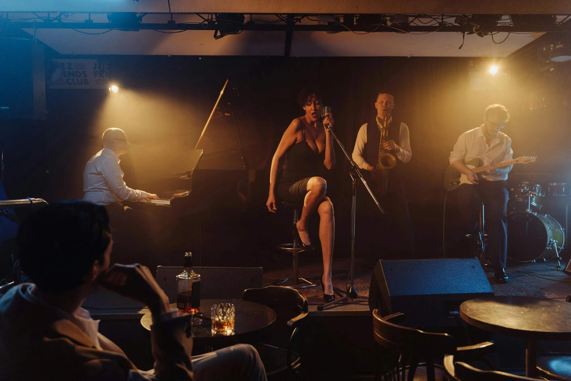 a group of men standing on top of a stage, a portrait, by Lee Loughridge, unsplash, art nouveau, film noir jazz bar, sitting in a lounge, music being played, 3 / 4 wide shot