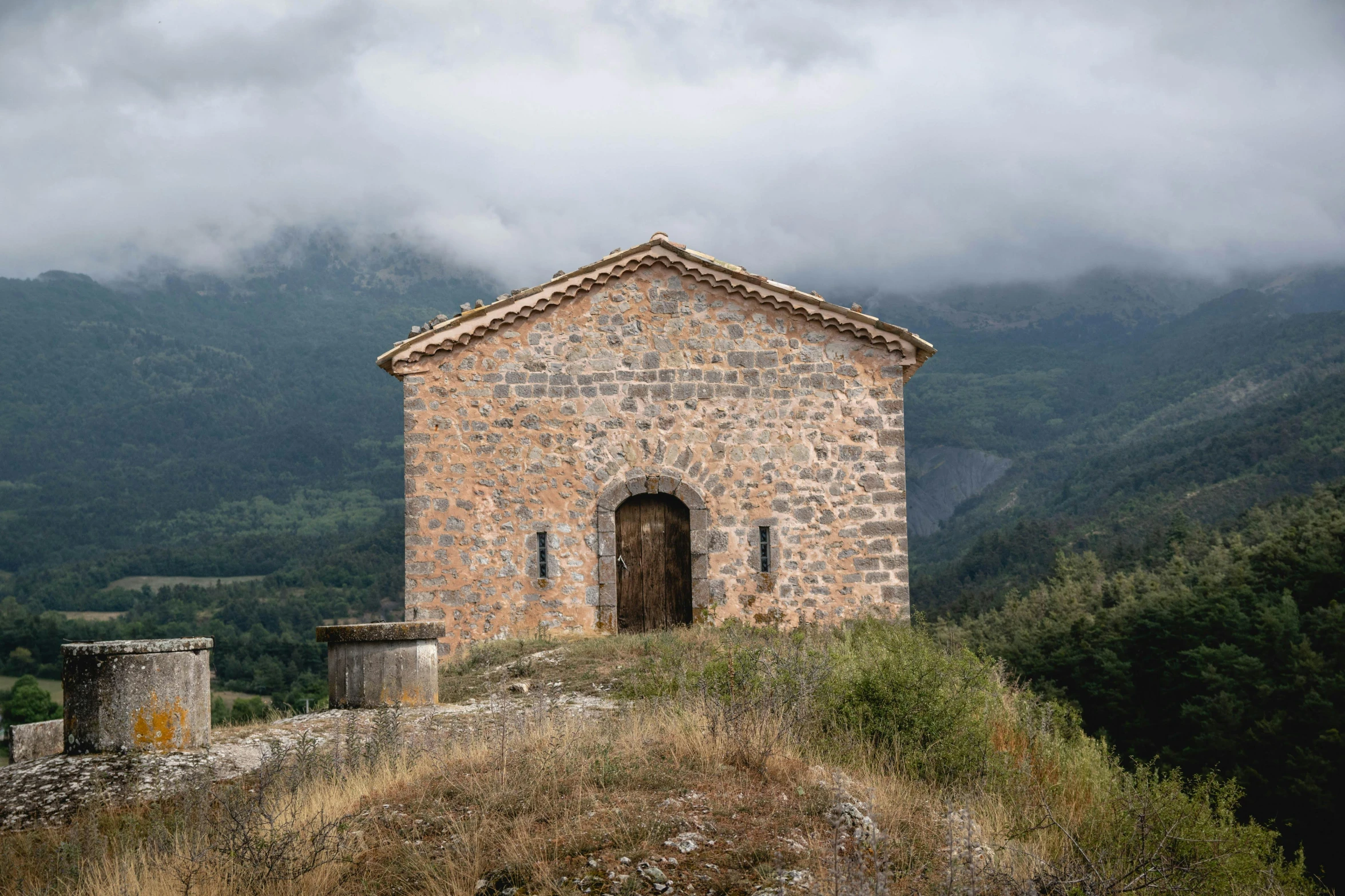 a small stone building sitting on top of a hill, inspired by Peter Zumthor, unsplash contest winner, romanesque, in spain, conde nast traveler photo, exterior photo, thumbnail