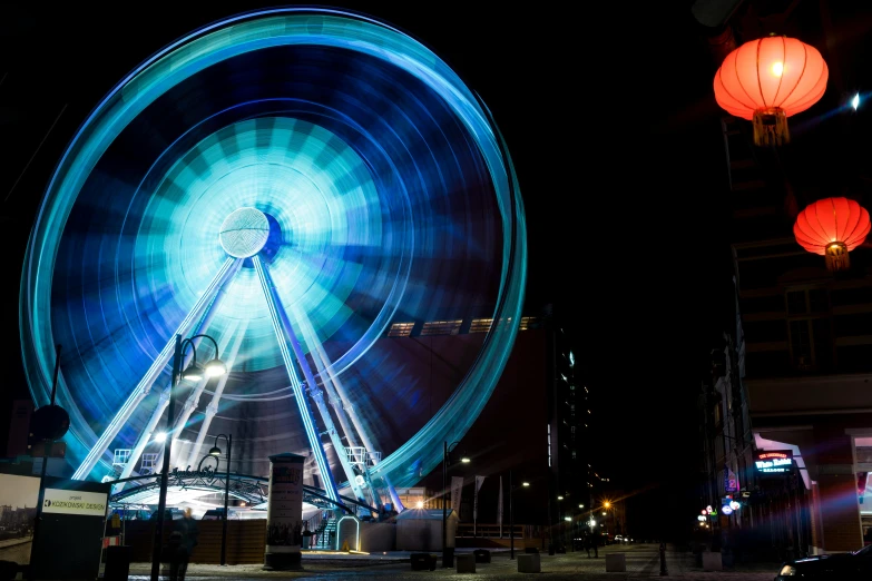 a ferris wheel in the middle of a city at night, by Lee Loughridge, unsplash contest winner, interactive art, lightpainting, coventry city centre, taken on a 2010s camera, vacation photo