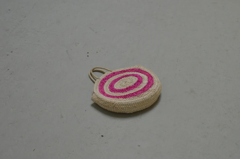 a pink and white purse sitting on top of a table, by Anna Boch, floating spiral sand, an unknown ethnographic object, round format, sold out piece