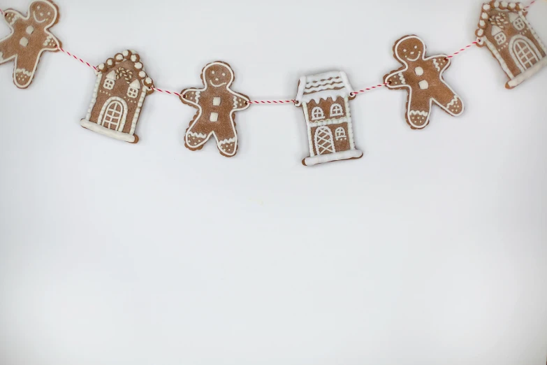 a group of gingerbreads hanging from a string, by Emma Andijewska, pexels contest winner, white houses, white backdrop, background image, full body image