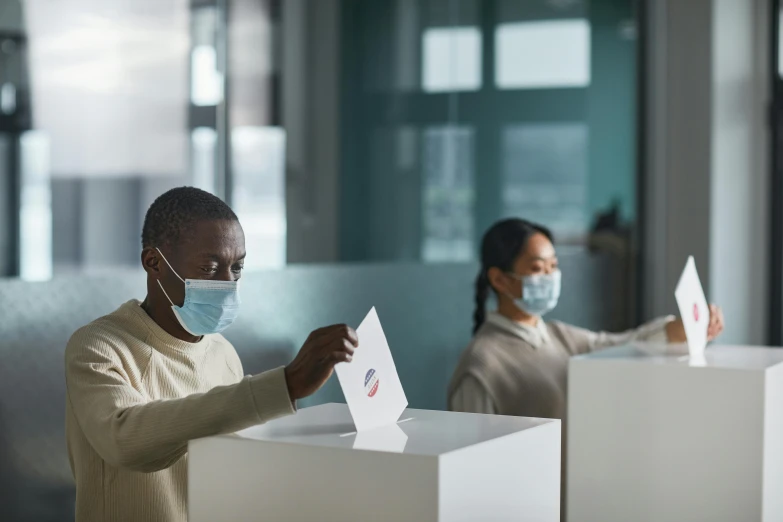 a man putting a voting paper into a voting box, a photo, by Meredith Dillman, pexels contest winner, renaissance, people are wearing masks, in an call centre office, square, obunga