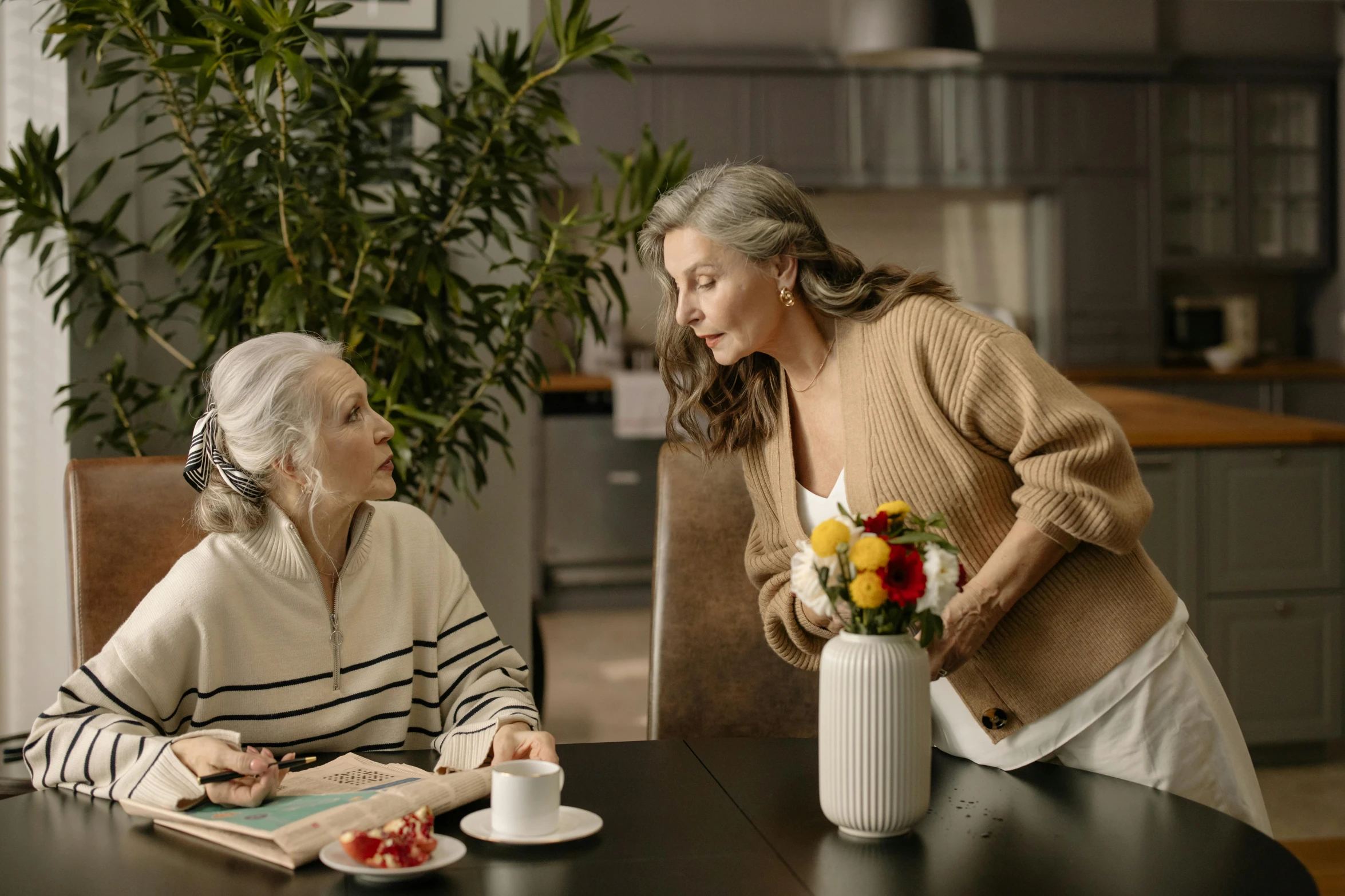 two women sitting at a table with a vase of flowers, pexels contest winner, gray haired, 15081959 21121991 01012000 4k, [ cinematic, brown