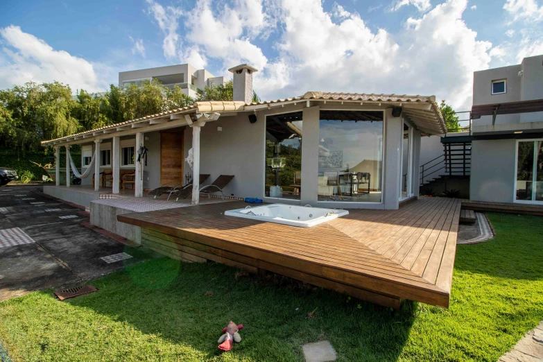 a hot tub sitting on top of a wooden deck, by Felipe Seade, villa, near the sea, profile image, lawn