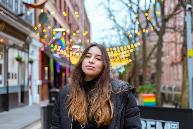 a woman standing in the middle of a city street, an album cover, by Julia Pishtar, pexels contest winner, lgbtq, wearing festive clothing, calm face, university