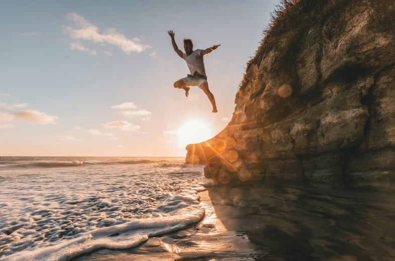 a man jumping off a cliff into the ocean, pexels contest winner, avatar image, golden hour photo, over a chalk cliff, high quality image