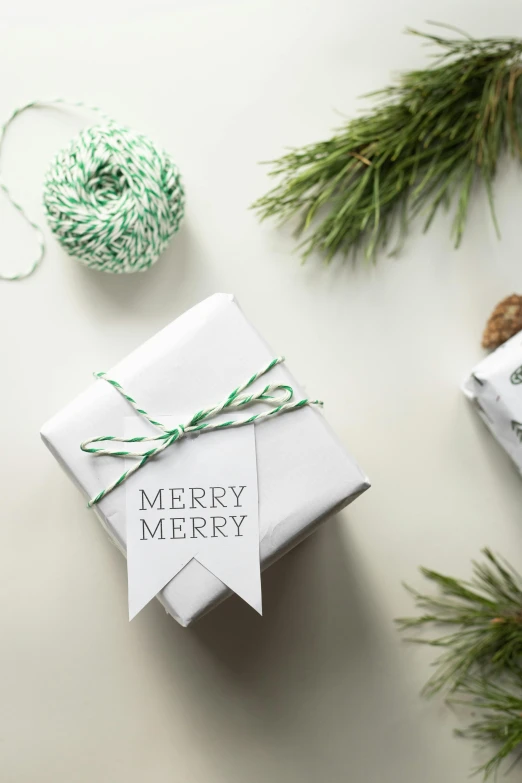 a couple of presents sitting on top of a table, green and white, merry, label, on white paper