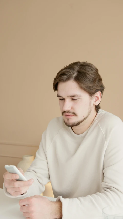 a man sitting at a table using a cell phone, discord profile picture, scowl, background image, brown haired