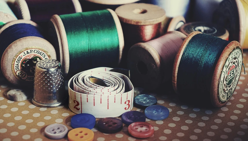 a bunch of spools of thread sitting on top of a table, a picture, by Sylvia Wishart, unsplash, arts and crafts movement, buttons, satin ribbons, green and brown clothes, instagram picture