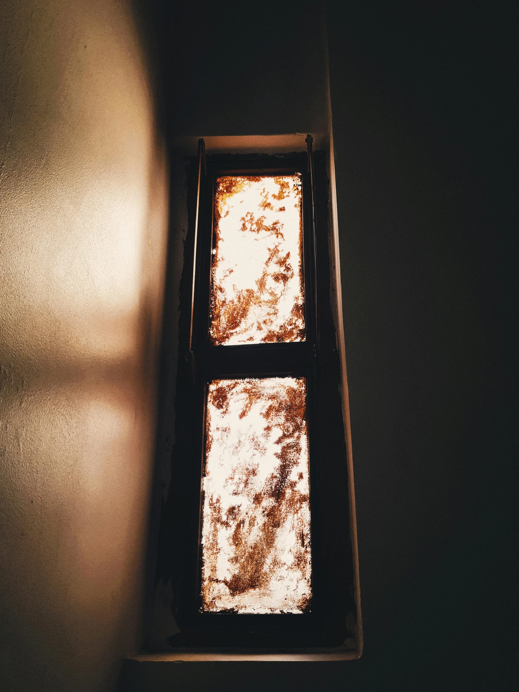 a light shines through a window in a dark room, an album cover, inspired by Elsa Bleda, unsplash, light and space, rust and plaster materials, glowing gold embers, snapchat photo, white warm illumination