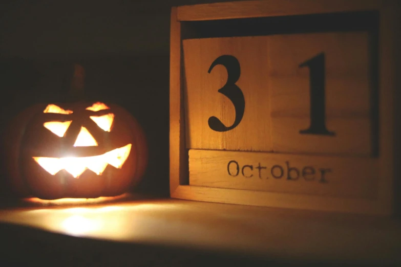 a wooden block with a carved pumpkin next to it, by Helen Stevenson, pexels, happening, countdown, lantern light besides, costume, ( 3 1