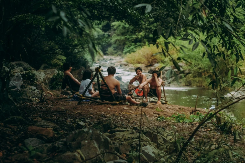 a group of people sitting next to a river, by Jessie Algie, pexels contest winner, tamborine, pipe jungle, avatar image