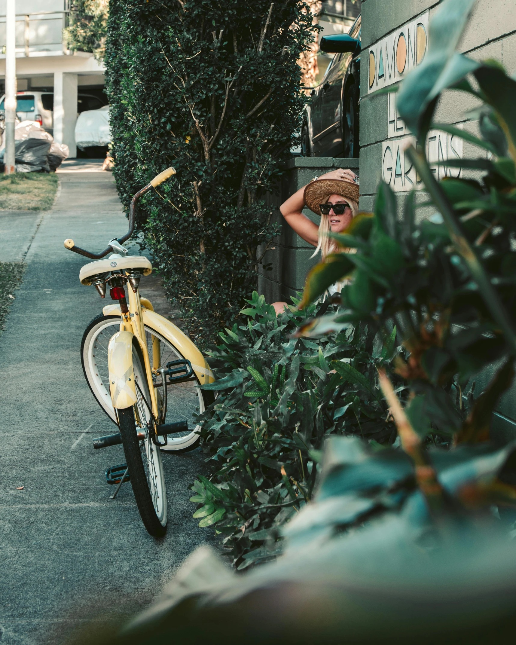 a yellow bicycle parked on the side of a street, by Carey Morris, pexels contest winner, lush greenery, photo of a woman, manly, forward facing