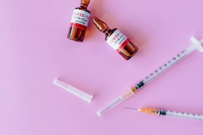 a syll, a bottle of medicine and a syll on a pink background, by Julia Pishtar, trending on pexels, syringe, white and red color scheme, coronavirus, brown