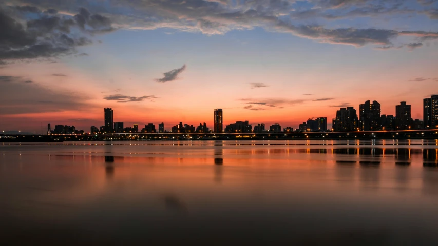 a large body of water with a city in the background, by Joseph Severn, pexels contest winner, hurufiyya, sunset panorama, pyongyang, karachi skyline background, nature photo