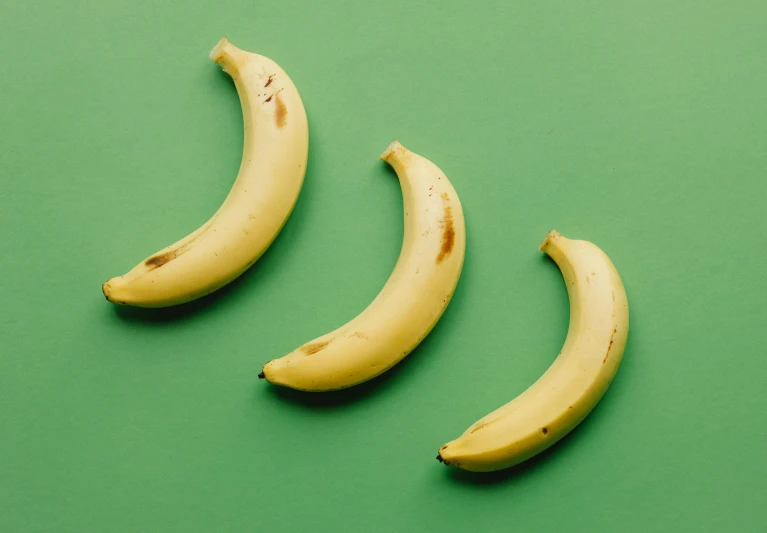 three bananas sitting next to each other on a green surface, trending on pexels, stomach vibes, highly upvoted, vanilla, various sizes