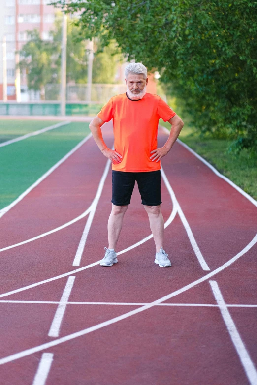 a man standing on a track with his hands on his hips, atrophy, hide the pain harold, red sport clothing, promo image