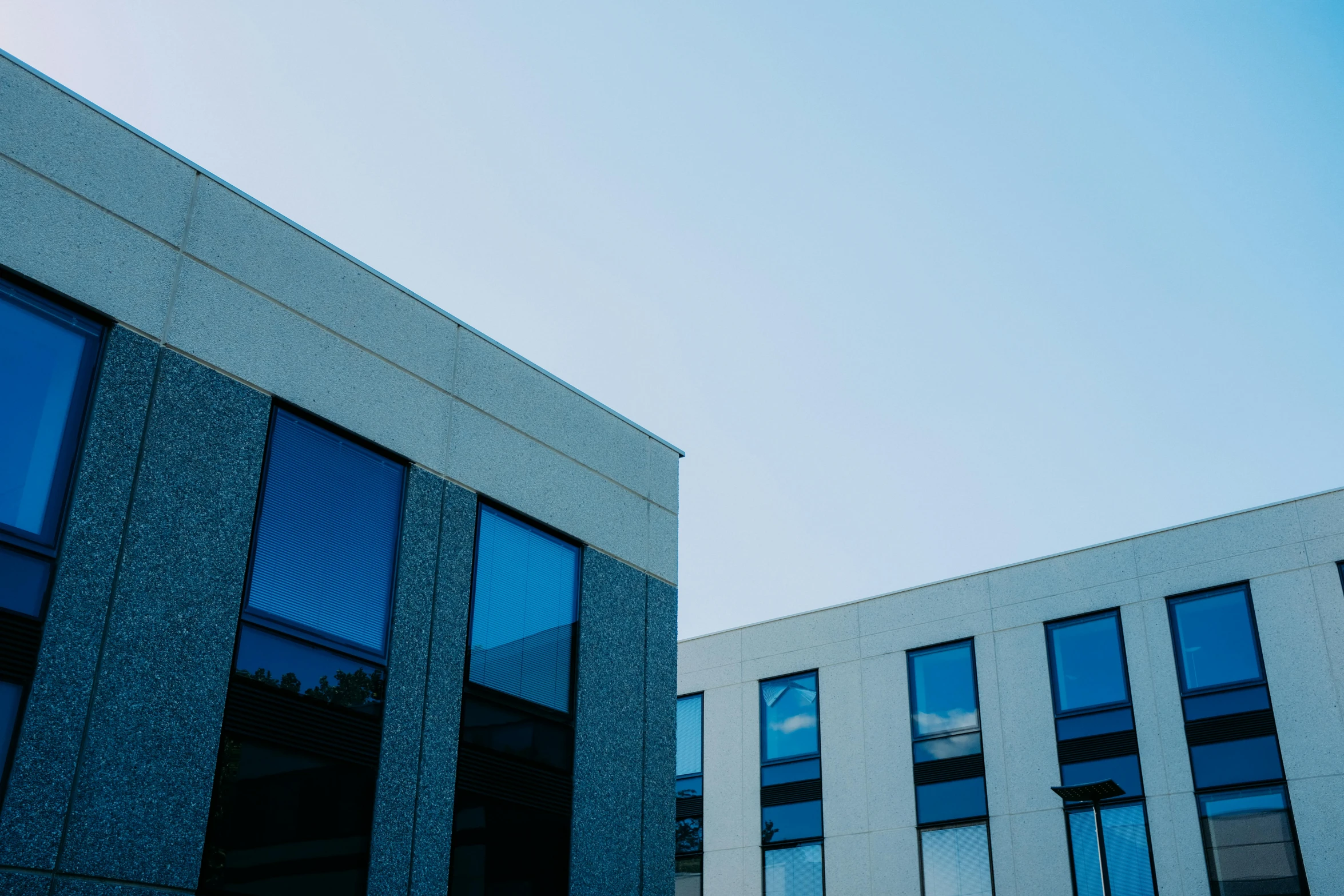 a couple of buildings that are next to each other, a photo, unsplash, modernism, soft grey and blue natural light, plain uniform sky, black windows, uploaded