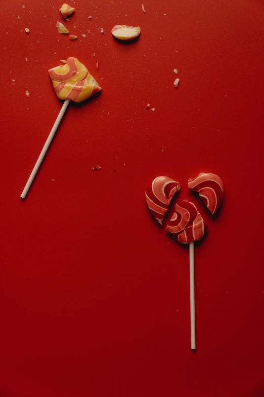 a couple of lollipops sitting on top of a red table, by Elsa Bleda, epicurious, falling hearts, profile image, made of glazed