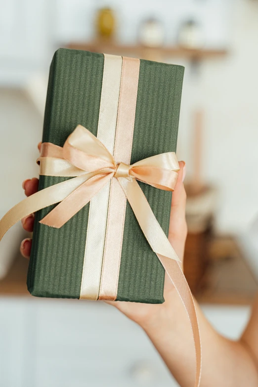 a woman holding a green wrapped present in a kitchen, inspired by Eden Box, golden ribbon, uncropped, romantic lead, large tall
