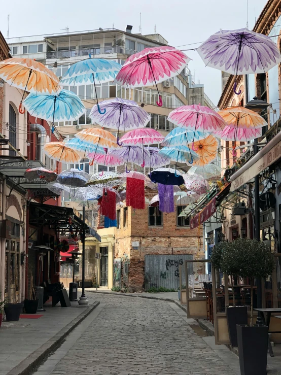 a street filled with lots of different colored umbrellas, by Niyazi Selimoglu, unsplash contest winner, street art, old city, slide show, baris yesilbas, colonial era street