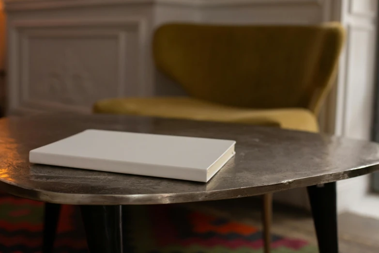 a book sitting on top of a table next to a chair, light grey, very large, table, rectangle