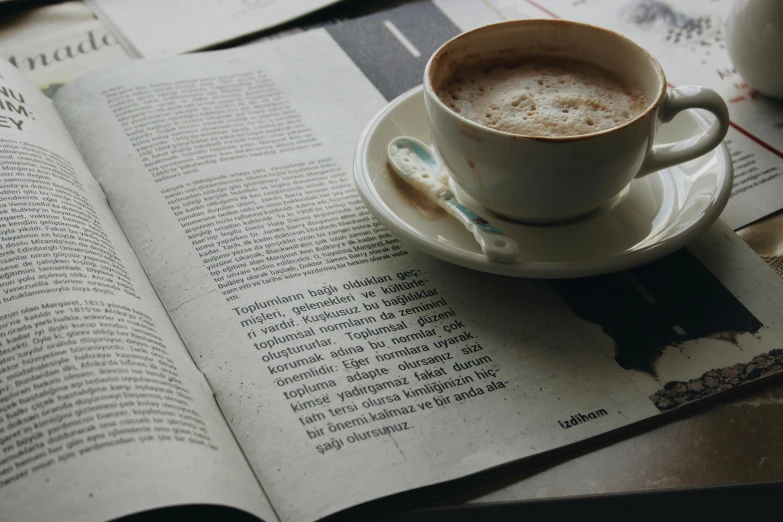 a cup of coffee sitting on top of an open book, a photo, pexels contest winner, private press, brown and white color scheme, language, text on paper, thumbnail