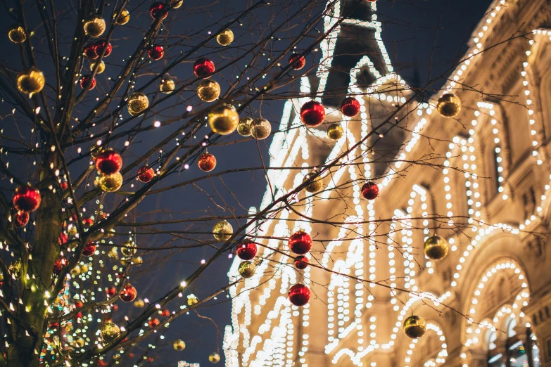 a lighted christmas tree in front of a building, by Zofia Stryjenska, pexels contest winner, hanging lanterns, zoomed in shots, square, moscow