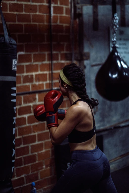 a woman standing next to a punching bag, by Arabella Rankin, pexels contest winner, happening, sports bra, profile image, sparring, back facing