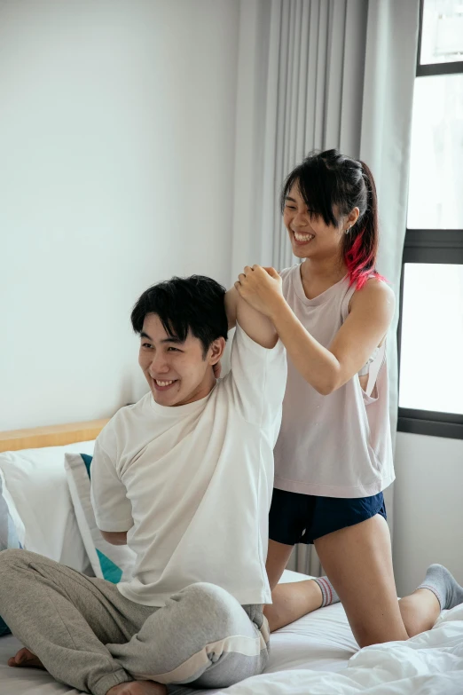 a man sitting on top of a bed next to a woman, by Reuben Tam, pexels contest winner, happening, waist reaching ponytail, wearing a t-shirt, joy ang, wearing a towel