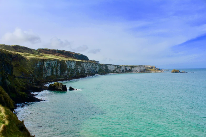 a large body of water next to a cliff, by Anna Findlay, pexels contest winner, sea - green and white clothes, ireland, slide show, blue