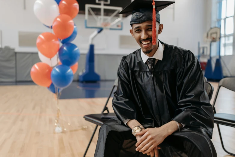 a man in a graduation cap and gown sitting on a chair, ashteroth, khyzyl saleem, background image, private school