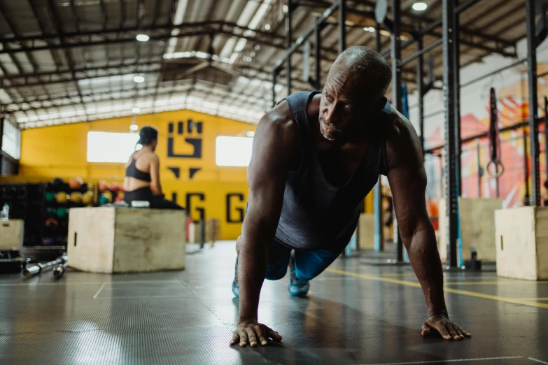 a man doing push ups in a gym, a photo, pexels contest winner, man is with black skin, old man doing hard work, background image, in a warehouse