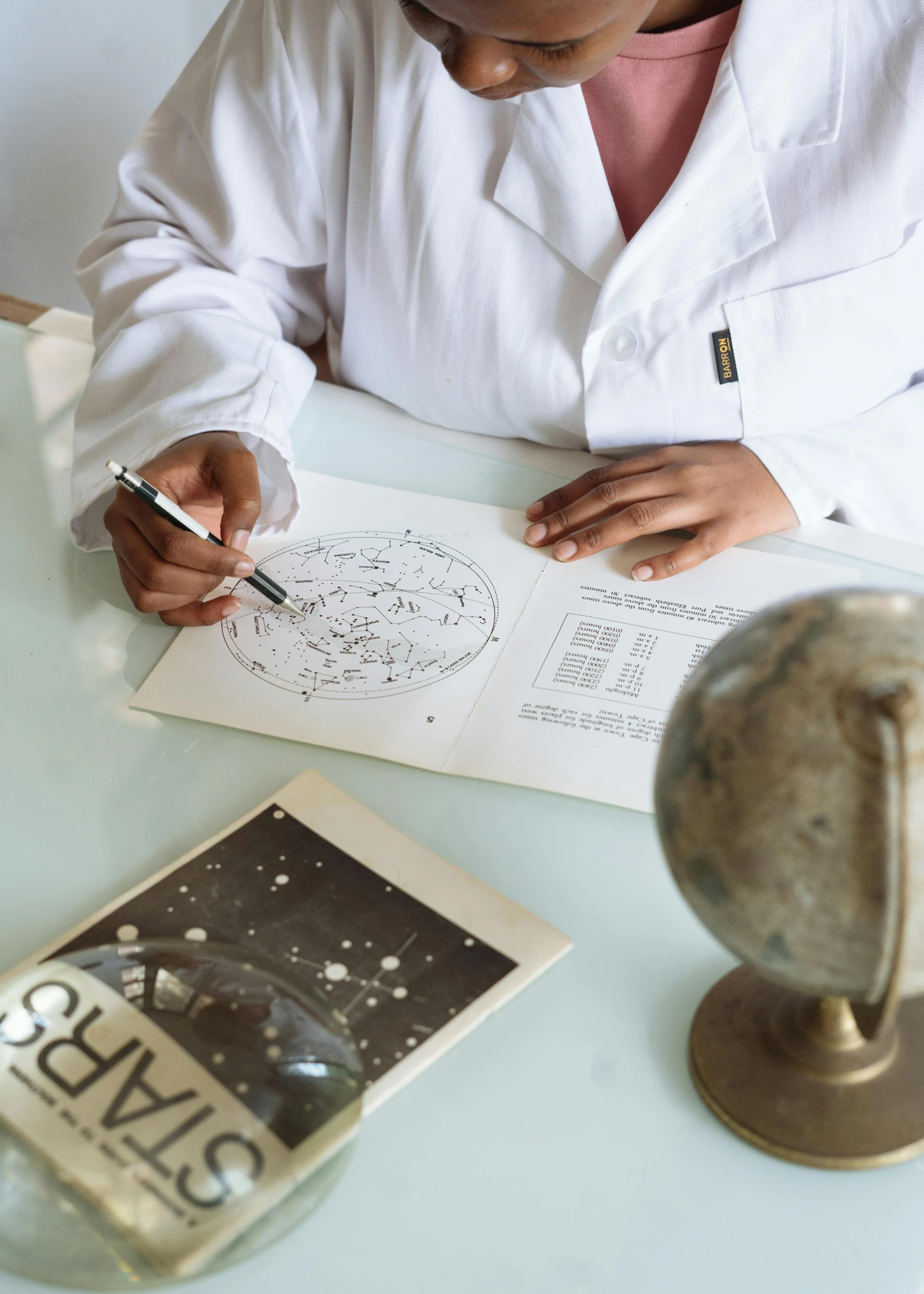 a woman in a lab coat writing on a piece of paper, a child's drawing, by Julia Pishtar, trending on unsplash, academic art, star map, with one vintage book on a table, scientific schematics, full product shot