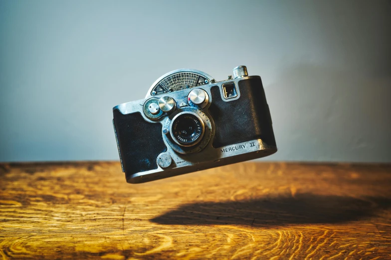 a camera sitting on top of a wooden table, by Matthias Stom, unsplash, photorealism, jumping at the viewer, 1940s photography, medium format. soft light, 35mm of a very cute