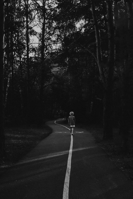 a person riding a bike down a tree lined road, a black and white photo, inspired by Diane Arbus, unsplash contest winner, girl walking in dark forest, horror wallpaper aesthetic, broken road, ✨🕌🌙