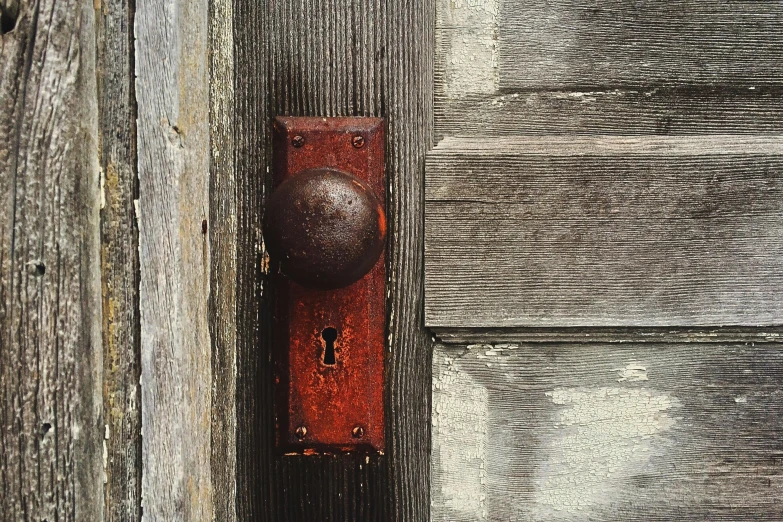 a close up of a door handle on a wooden door, an album cover, inspired by William Harnett, unsplash, assemblage, rusty red helmet, square, 2000s photo, outdoor photo