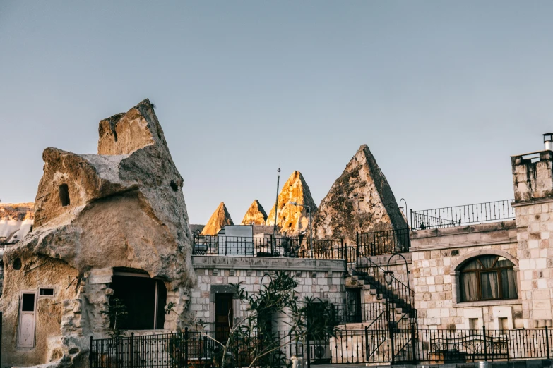 a stone building with a staircase in front of it, pexels contest winner, black domes and spires, rooftop romantic, tessellated planes of rock, prop rocks