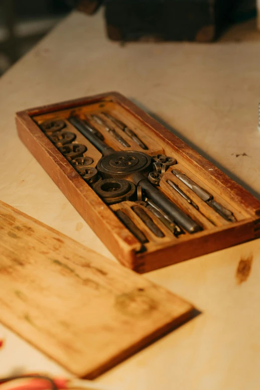 a wooden box filled with tools sitting on top of a table, a woodcut, unsplash, assemblage, machine parts, engraved blade, product display photograph, rust