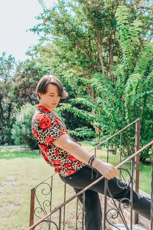 a woman sitting on top of a set of stairs, an album cover, unsplash, androgynous male, with hawaiian shirt, in a garden, in spain