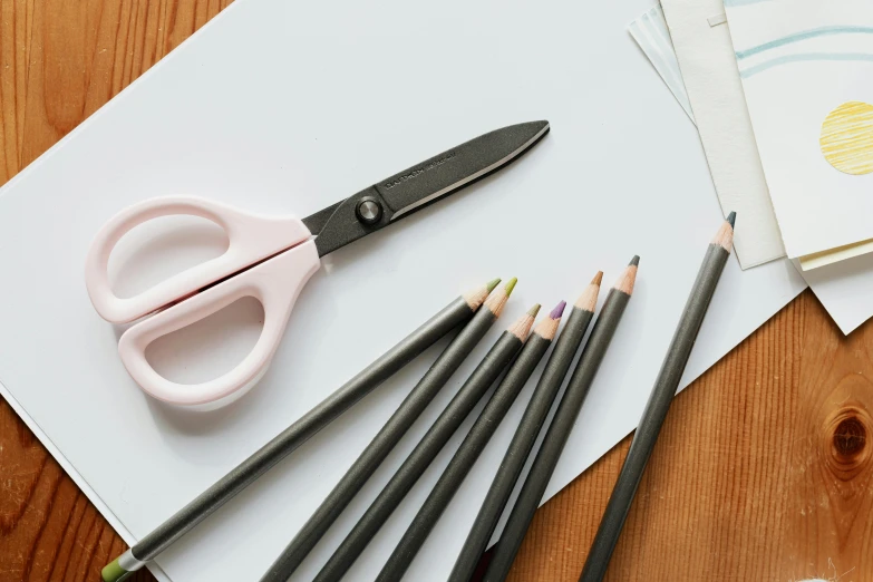 a pair of scissors sitting on top of a piece of paper, a child's drawing, inspired by Gerard David, pexels contest winner, process art, pencils, art set, no - text no - logo, medium: black pencil