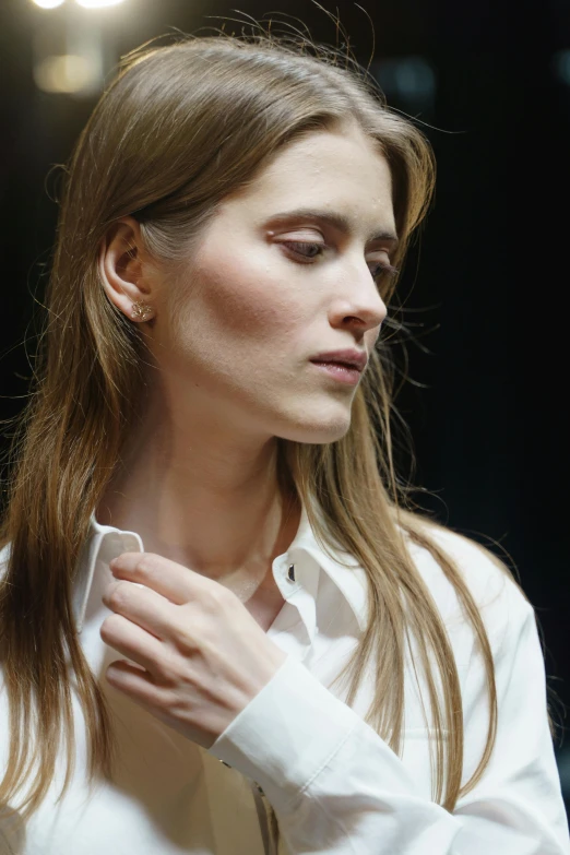 a woman in a white shirt adjusting her tie, trending on reddit, photorealism, runway photo, prominent jawline, hammershøi, delicate soft hazy lighting